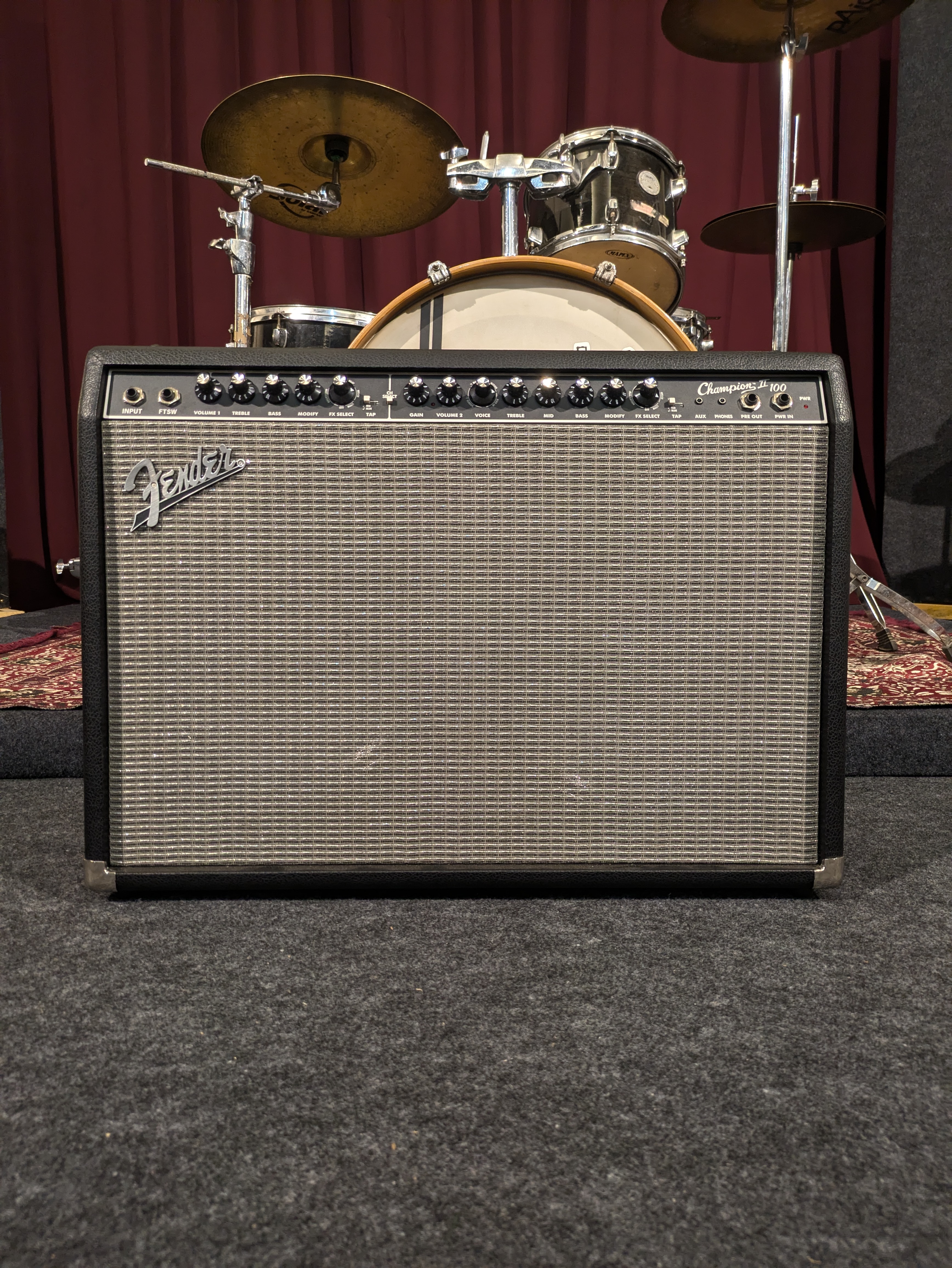 Fender Champion 100 combo amplifier standing in front of the drum kit