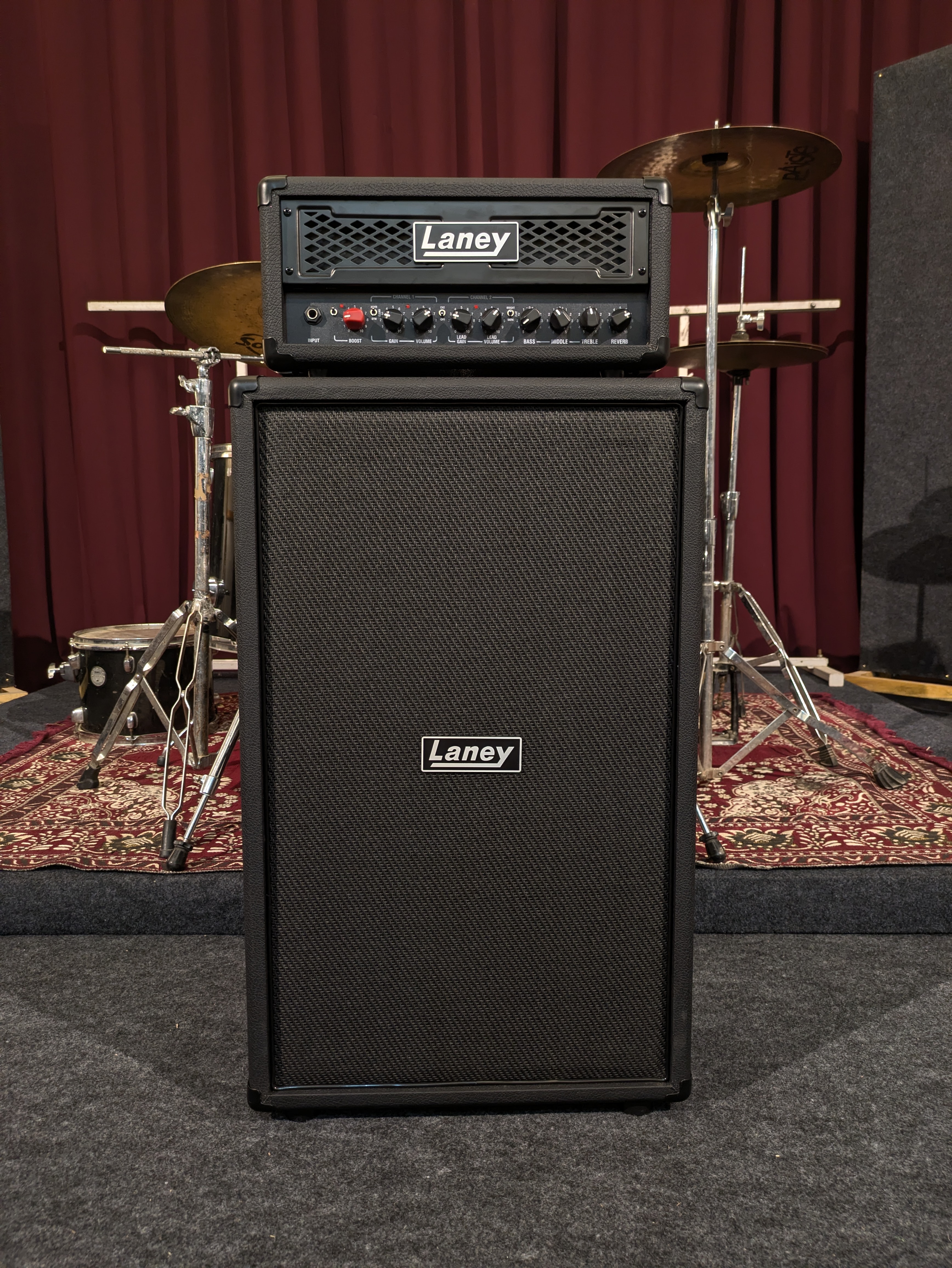 Laney guitar amplifier head on a matching 4x12 cabinet, on the stage in front of the drum kit
